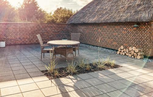 a patio with a table and chairs and a brick wall at Gorgeous Home In Ulfborg With Sauna in Ulfborg
