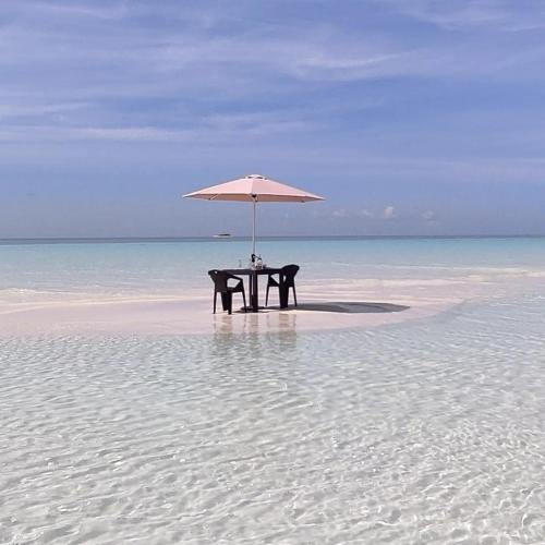 a table with an umbrella on a beach at Himandhoo sweet dreams in Himandhoo 