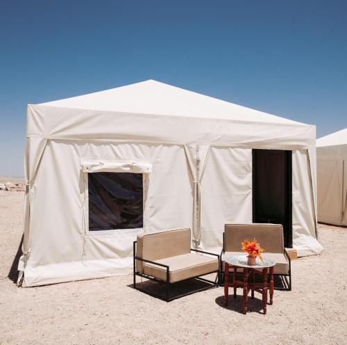 a tent with two chairs and a table in the desert at Les Terrasses d'Agafay in El Karia
