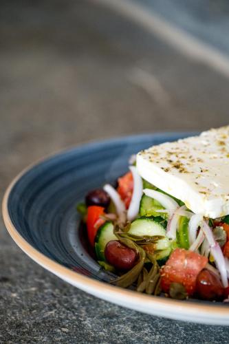 a blue plate with a salad with cheese and vegetables at Anthea Hotel in Tinos Town