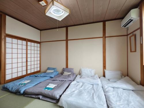 two twin beds in a room with a wall at 旅館青柳 海越し立山連峰の雪山絶景で休もう in Himi