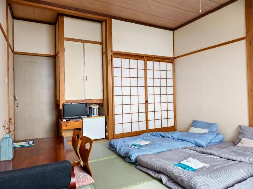 a room with two beds and a tv in it at 旅館青柳 海越し立山連峰の雪山絶景で休もう in Himi