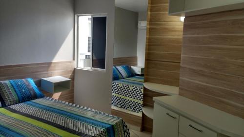 um pequeno quarto com 2 camas e um espelho em Apart Cote D'Azur Maceió em Maceió