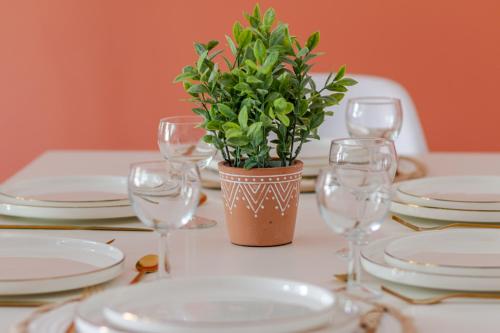 a table with glasses and a potted plant on it at Le Chaleureux - 5 min Disneyland - Parking - Netflix - Wifi in Serris