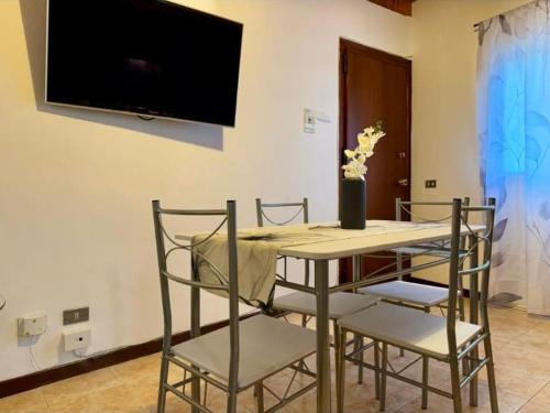 a dining room table with chairs and a television on a wall at Mediterranea Apartment in Agrigento