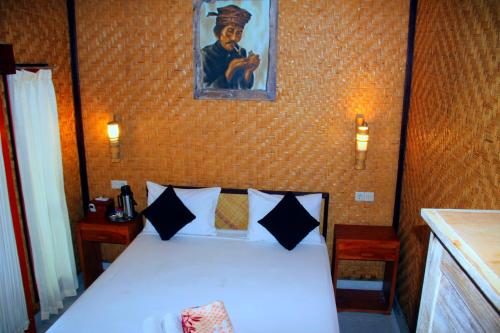 a bedroom with a white bed with a painting on the wall at Gara menjangan homestay in Banyuwedang