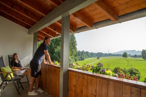 a man standing on a balcony looking out at a garden at Berger's Bergsicht by edita in Scheidegg