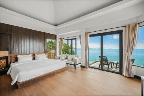 a bedroom with a bed and a large window at The Kala in Amphoe Koh Samui