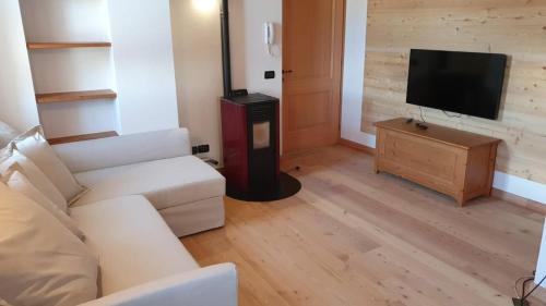 a living room with a white couch and a television at Sunny and cosy holiday apartment in the Dolomites in Pianaz