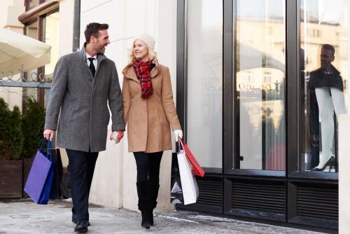 a man and woman walking down a street with shopping bags at The Moment Luxury Suites in Parndorf