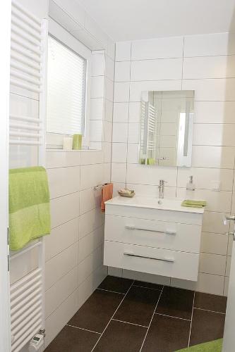 La salle de bains blanche est pourvue d'un lavabo et d'un miroir. dans l'établissement business + life apartment ferienwohnung, à Ransbach-Baumbach