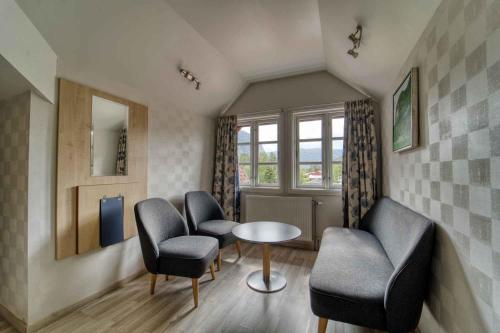 a waiting room with chairs and a table and a window at Sølvgarden Hotel in Rysstad