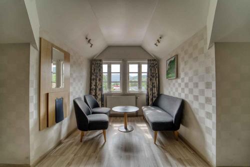 a living room with two chairs and a table at Sølvgarden Hotel in Rysstad