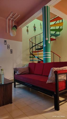 a living room with a red couch and stairs at yercaud Happy valley cottage in Yercaud
