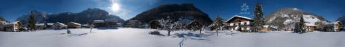 a snow covered field with houses and a mountain at Haus Arnika in Mellau