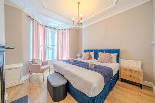 Sleeps 7- Spacious 3 Bed House w Free Parking في ليفربول: غرفة نوم كبيرة بسرير ازرق وكرسي