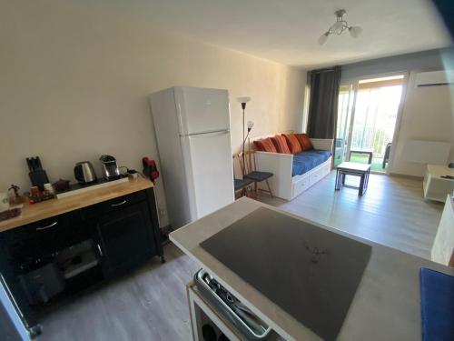 a kitchen and living room with a white refrigerator at Location appartement Sète vu sur mer in Sète