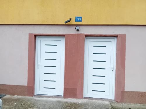 two white garage doors on the side of a building at Apartments AZRA in Konjic