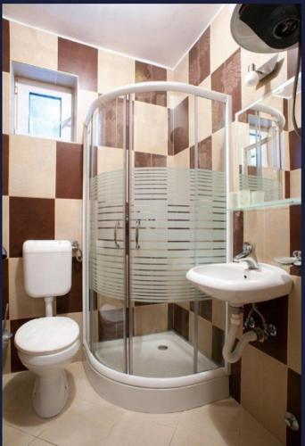a bathroom with a shower and a toilet and a sink at Turkuaz Boutique Hotel in Sveti Stefan