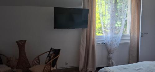 a bedroom with a tv on the wall next to a window at Les Escales de Marion in Le Val-Saint-Père