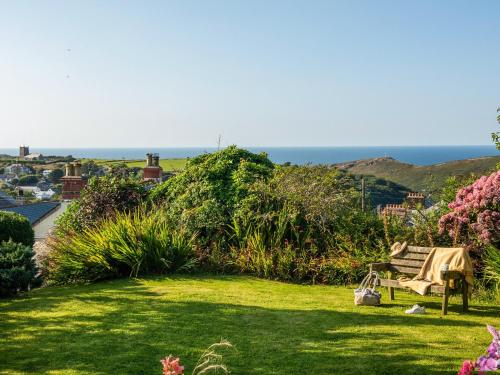 a garden with a bench and the ocean in the background at Trevivian House in Boscastle
