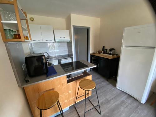 a kitchen with a refrigerator and two chairs in it at Location appartement Sète vu sur mer in Sète