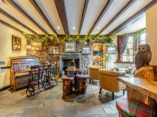 a living room with a stone fireplace and tables and chairs at The Tormaukin in Glendevon