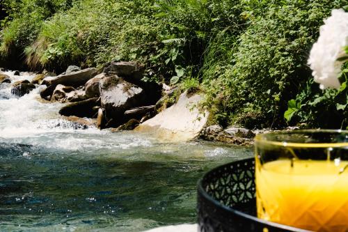 a drink sitting on a table next to a river at ONKL XONNA Premium Alpin Chalets in Hüttschlag