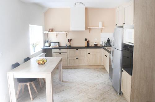 a kitchen with a table and a white refrigerator at Le Regeau, Chatillon Coligny in Châtillon-Coligny