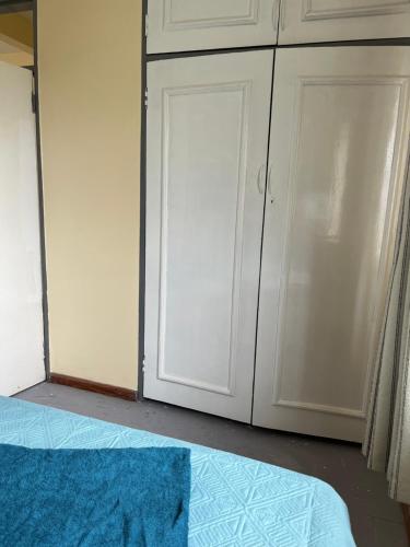 a bedroom with white cabinets and a blue rug next to a bed at Chandos Lodge in Lusaka