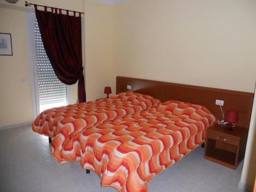 Hotel Polo في San Felice sul Panaro: سرير برتقالي كبير في غرفة النوم مع نافذة