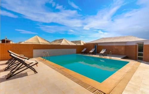 a swimming pool on the roof of a hotel with pyramids in the background at Arman Desert Luxury Camp & Resort Jaisalmer in Jaisalmer