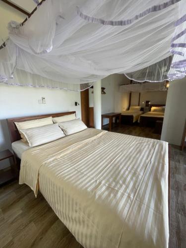 a bedroom with a large bed with a white canopy at Zion View Ella Green Retreat in Ella