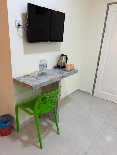 a desk with a green chair and a tv on the wall at D'Lima Beach Inn in Pantai Cenang