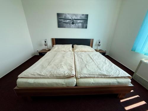 a large bed in a room with two night stands at Hotel CAVOK letiště Příbram in Drásov