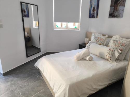 a white bed with pillows and a mirror in a bedroom at Violet Apartments in Msida