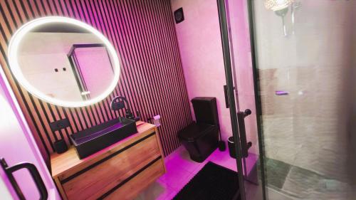 ein rosafarbenes Badezimmer mit einem Spiegel und einem Waschbecken in der Unterkunft Propiedad San Salvador in Mogán