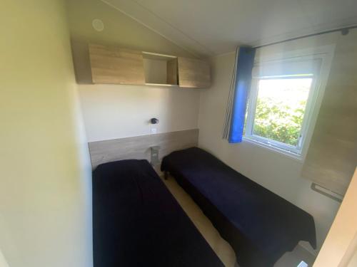 a small bedroom with a bed and a window at Camping Le Tarteron in Le Crotoy