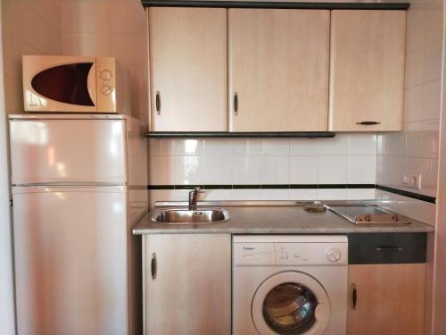 a kitchen with a white refrigerator and a sink at Apartamento Avenida del Parque in Cazorla