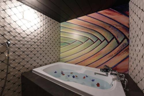 a bathroom with a bath tub with a painting on the wall at ホテル椿for adalt in Yokohama