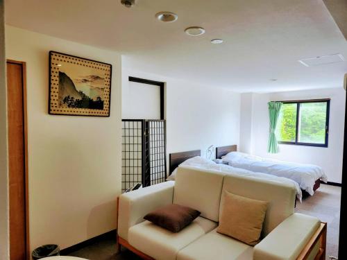 a living room with a couch and a bed at Toya-onsen Hotel Hanabi in Lake Toya