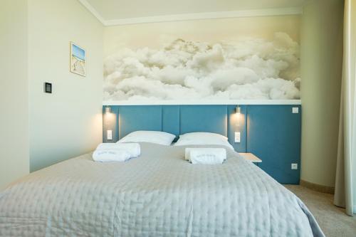 a bedroom with a large bed with clouds on the wall at Wave by Baltic Home in Międzyzdroje