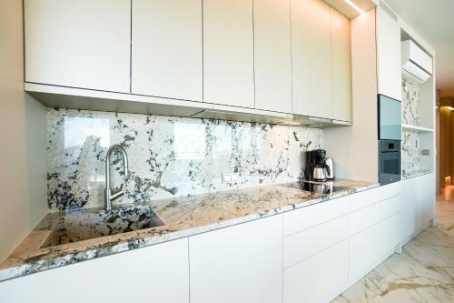a kitchen with white cabinets and a sink at Wave by Baltic Home in Międzyzdroje