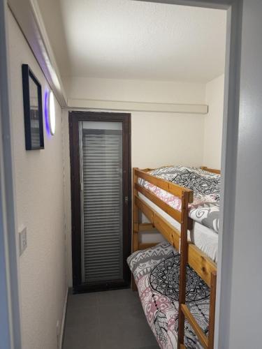 Cette petite chambre comprend des lits superposés et une porte. dans l'établissement Le Cap'rice, au Cap d'Agde