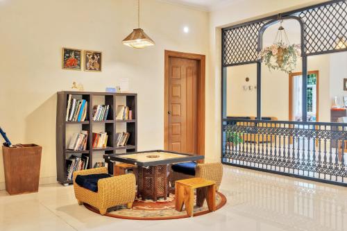a living room with a table and chairs and a book shelf at SaffronStays Robin Woods in Kenchamman Hoskota