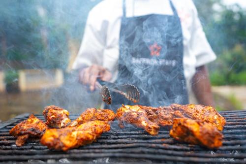 a man is cooking food on a grill at SaffronStays Robin Woods in Kenchamman Hoskota