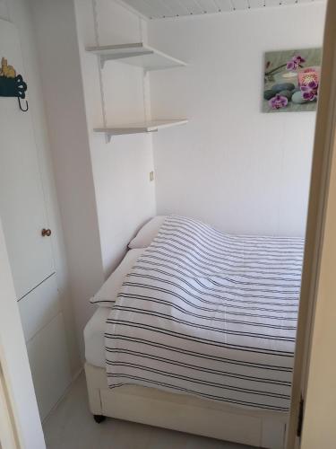 a small bedroom with a bed with striped sheets at Chalet with waterfront sauna and boat in Loosdrecht