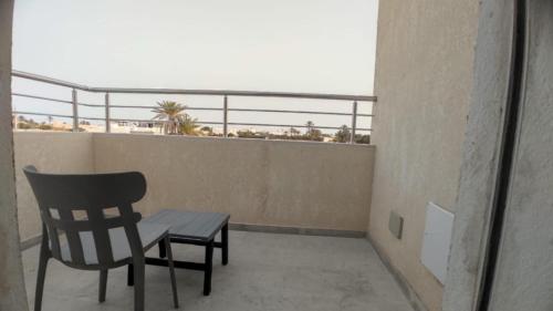 a chair and a table on a balcony at villa el amir in Banī Dinhet