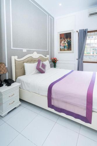 a white bedroom with a large bed with a purple blanket at Hanoi 0riental Hotel & Travel in Hanoi
