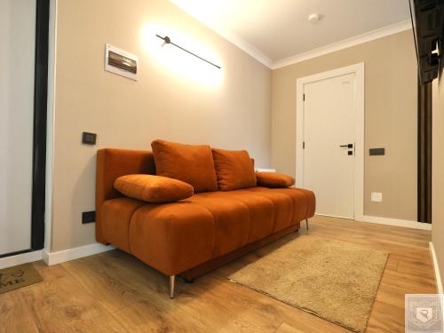 an orange couch in a room with a door at RentHouse Apartments - Airport Loft in Chişinău